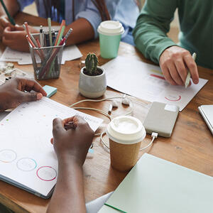 A group of people working on a project at a desk with cellphones and coffee